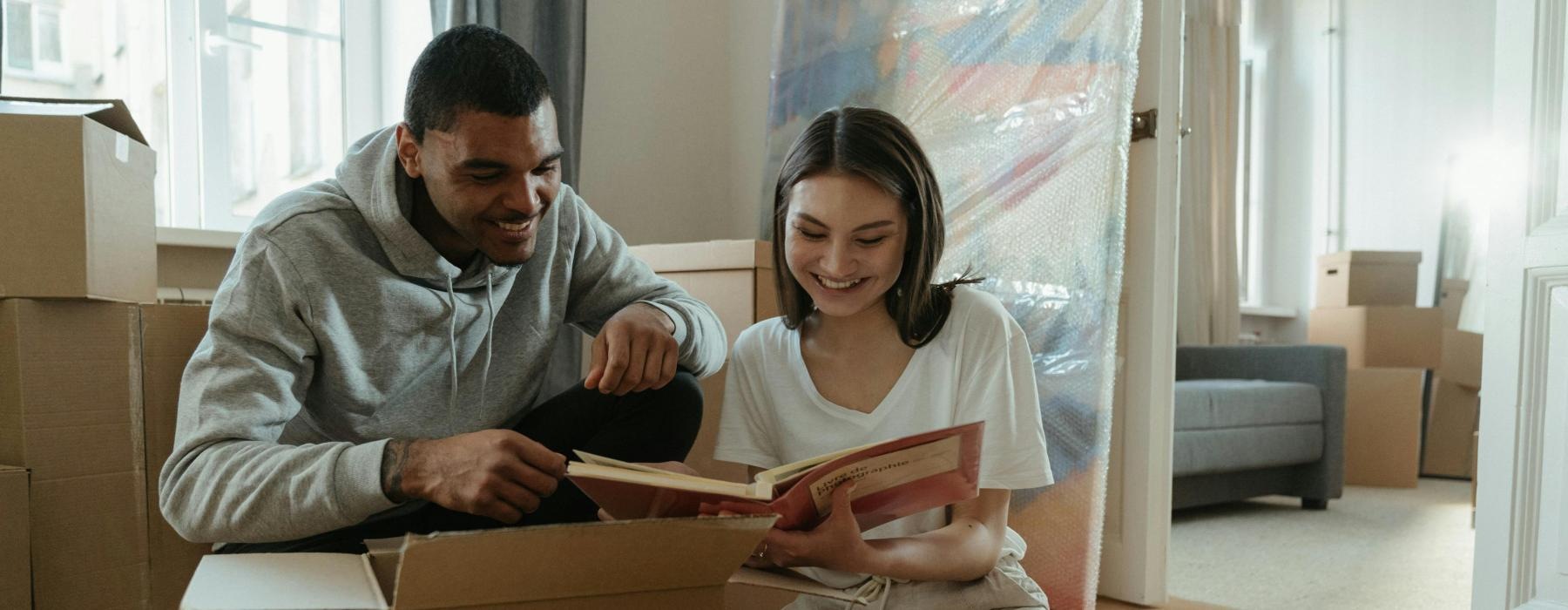 a man and a woman sitting on the floor reading a book
