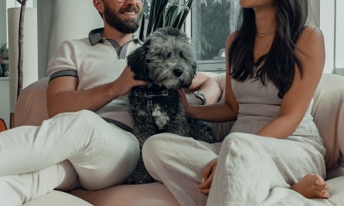 a man and woman sitting on a couch with a dog